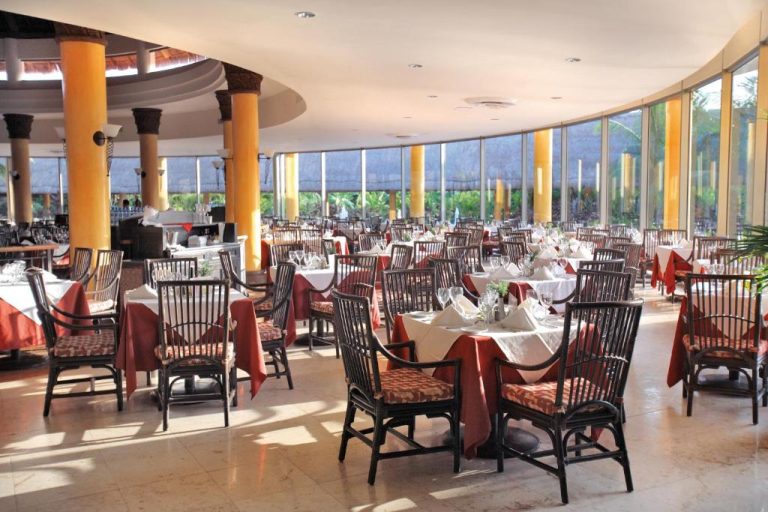 Amplio restaurante principal con mesas elegantes y vistas al jardín en Barceló Maya Tropical All Inclusive