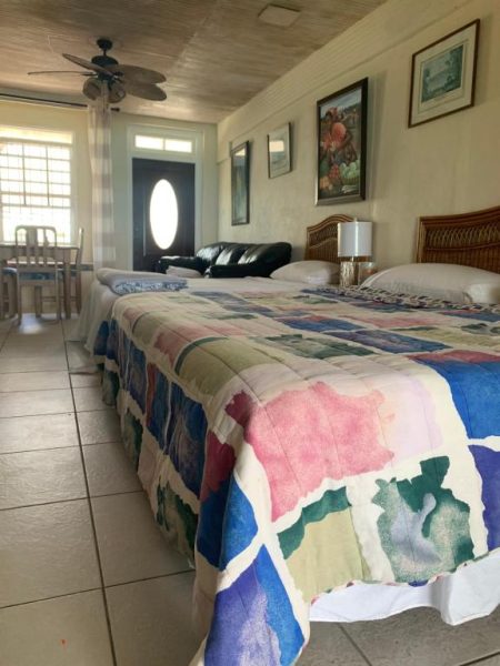 Habitación doble con camas y colcha multicolor en Beach Vue Barbados con ventilador de techo