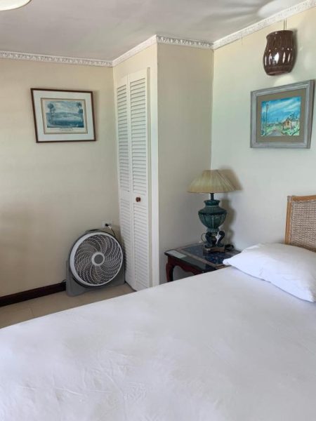 Habitación doble con cama matrimonial, ventilador de pie y mesita de noche en Beach Vue Barbados