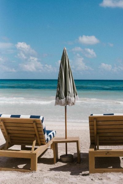 Tumbonas de madera con cojines a rayas azules y sombrilla en la playa del Hotel Panamera