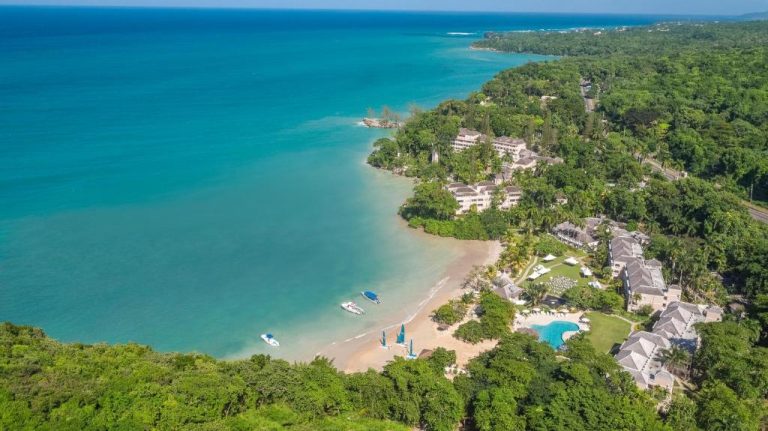 Vista aérea del resort Couples Sans Souci con playa privada y piscina rodeada de vegetación tropical en Jamaica