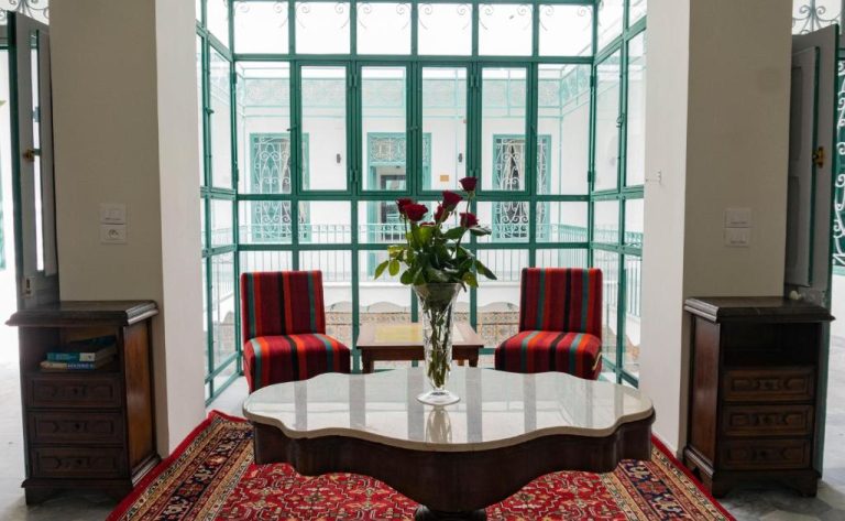 Elegante salón interior con patio acristalado y decoración árabe en Dar Ben Gacem Kahia