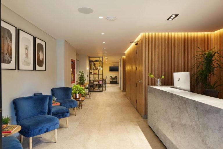 Recepción de mármol y zona de espera con sillas azules en el lobby del 14 Urban Hotel