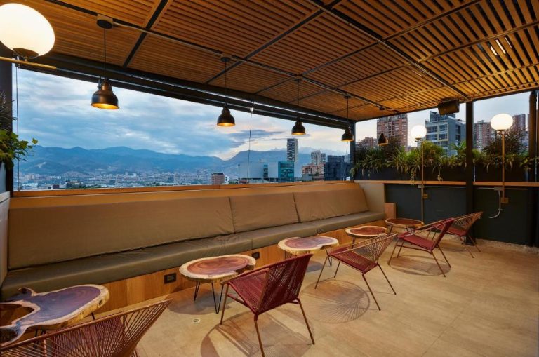 Terraza rooftop del 14 Urban Hotel con sofás, mesas de madera y vistas panorámicas a la ciudad y montañas