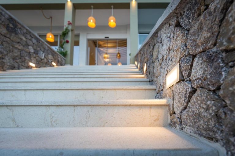 Escaleras de mármol iluminadas con luces empotradas y muros de piedra en Eleals Boutique Hotel
