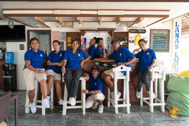 Personal del Lanas Beach Resort en Carabao Island posando junto al bar Lanas Lounge con uniformes azules