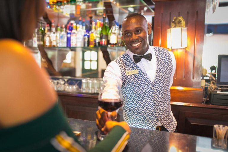 Bartender sonriente sirviendo copa de vino tinto en el bar del Courtleigh Hotel & Suites Jamaica