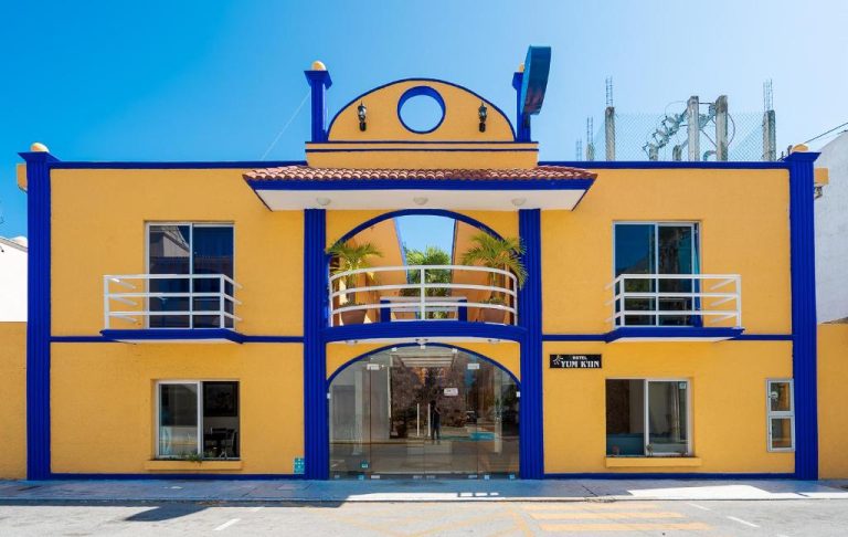Fachada exterior amarilla y azul del Hotel Yumkiin, cerca del Ferry y Terminal ADO en México