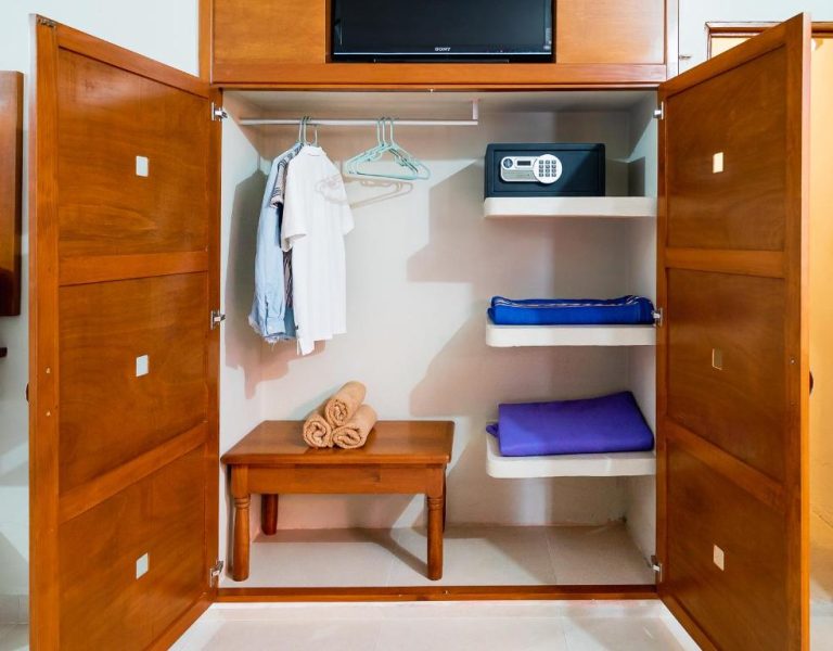 Armario de madera con caja fuerte, perchas y estantes con toallas en habitación del Hotel Yumkiin