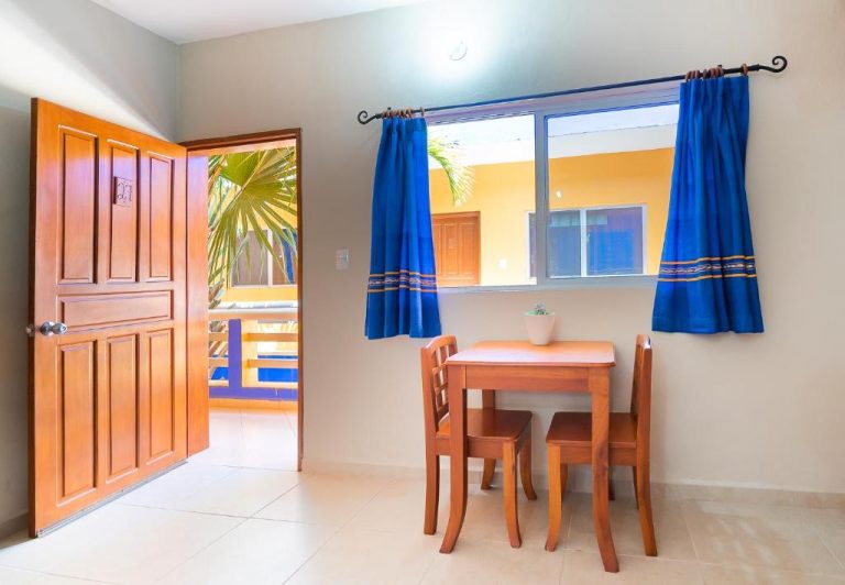Habitación con mesa de comedor de madera y cortinas azules en Hotel Yumkiin cerca del Ferry y Terminal ADO