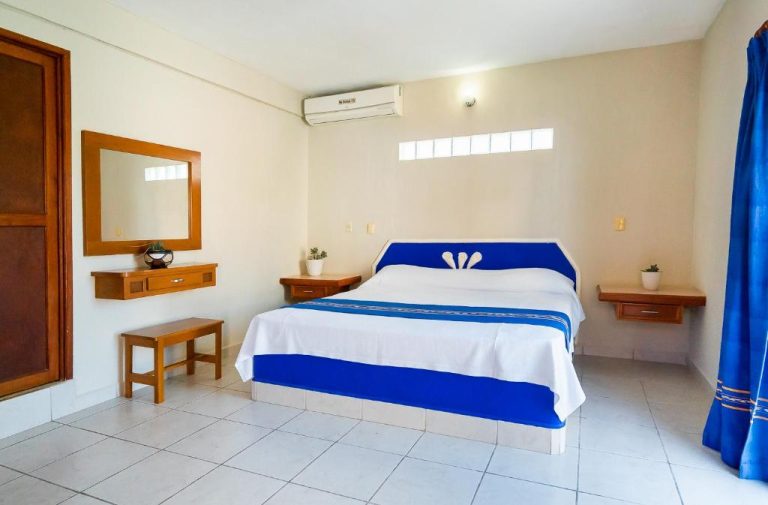 Habitación doble con cama matrimonial azul y blanca en Hotel Yumkiin, cerca del Ferry y Terminal ADO