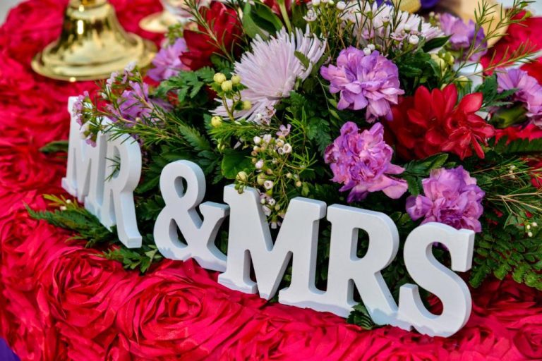 Decoración nupcial con letras Mr & Mrs y flores moradas y rojas en Coco La Palm