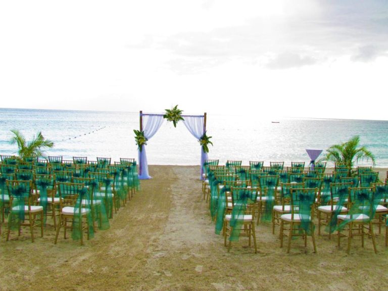 Ceremonia de boda en la playa del Coco La Palm con sillas doradas y arco decorado frente al mar