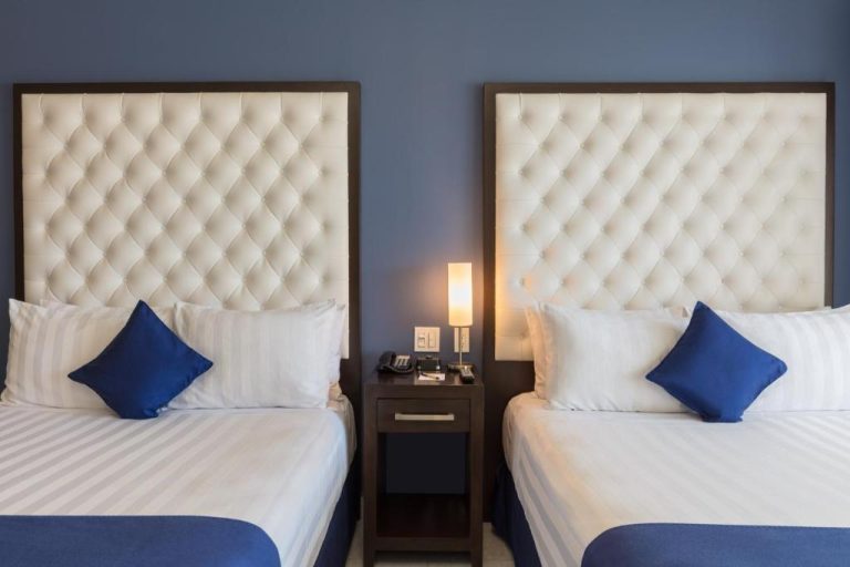 Habitación doble con dos camas individuales y cabeceros tapizados en blanco en Medano Hotel and Spa