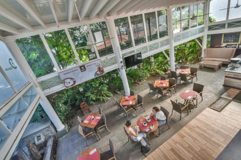Terraza cafetería con mesas y vegetación tropical del La Riviera Hotel vista desde altura