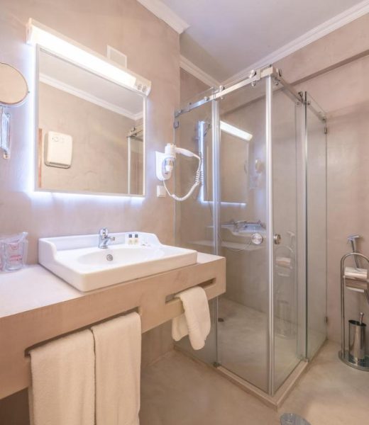 Baño moderno con ducha de cristal y lavabo del Loule Jardim Hotel en el Algarve