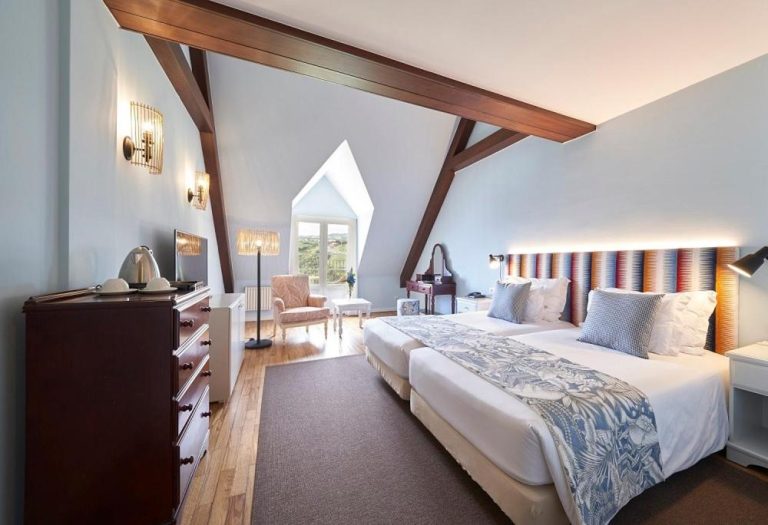 Habitación abuhardillada con vigas de madera y camas dobles en Hotel Quinta do Furao