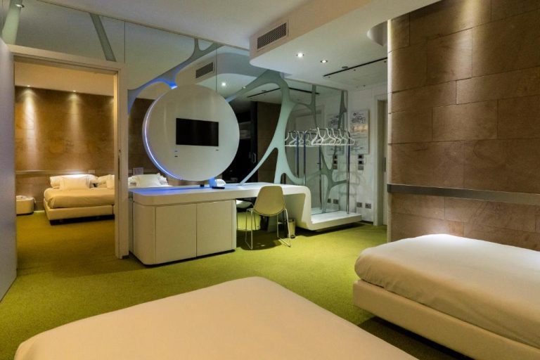 Habitación de diseño futurista con TV circular y moqueta verde en A Point Arezzo Park Hotel
