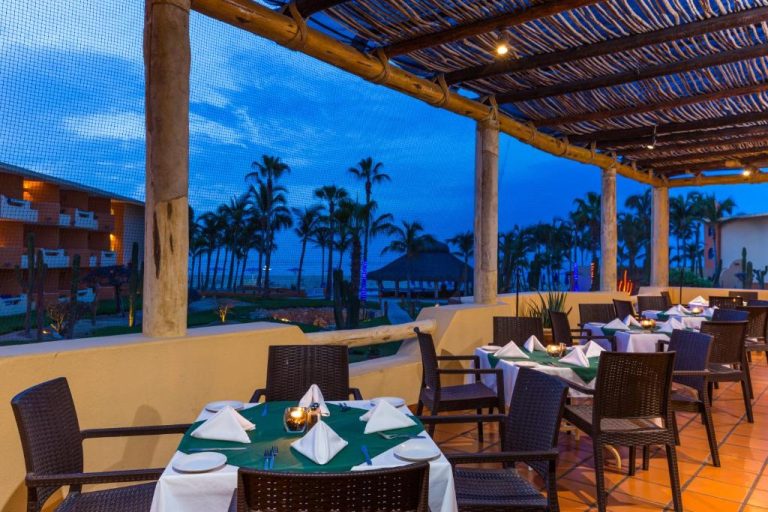 Restaurante terraza con vista al mar al atardecer en Posada Real Los Cabos, mesas elegantes con velas