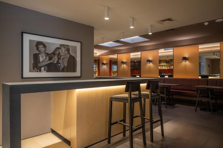 Bar lounge elegante con taburetes y decoración moderna en el Hotel Girassol Suite Hotel