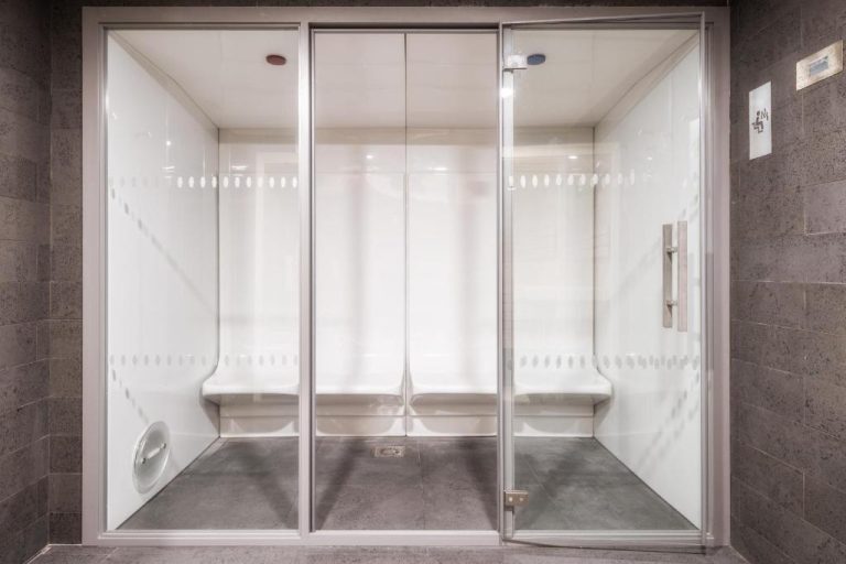 Cabina de sauna y baño de vapor con paredes blancas y puertas de cristal en Hotel Girassol Suite Hotel