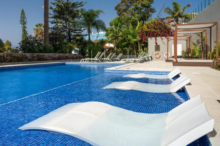 Piscina exterior con tumbonas flotantes y zona de relax del Hotel Girassol Suite Hotel