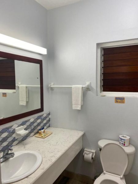 Baño completo con lavabo, inodoro y espejo iluminado en Toby's Resort