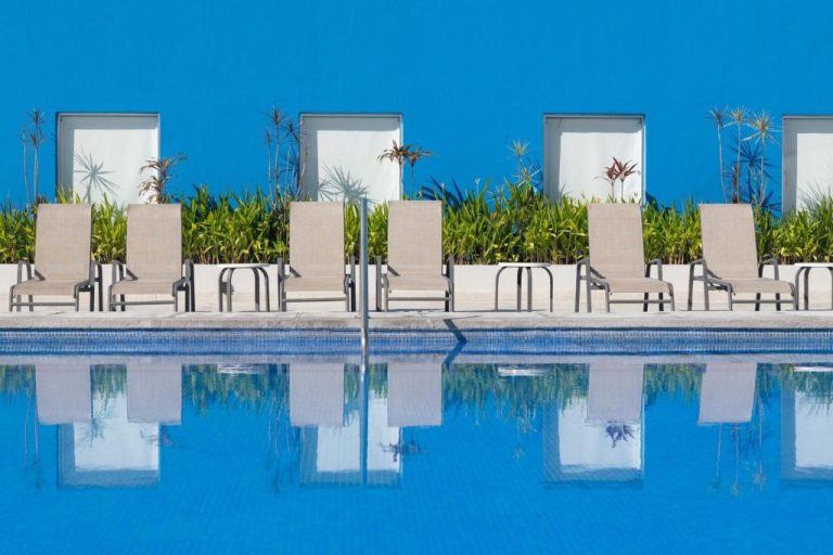 Piscina exterior con tumbonas y vegetación tropical del One Puerto Vallarta Aeropuerto