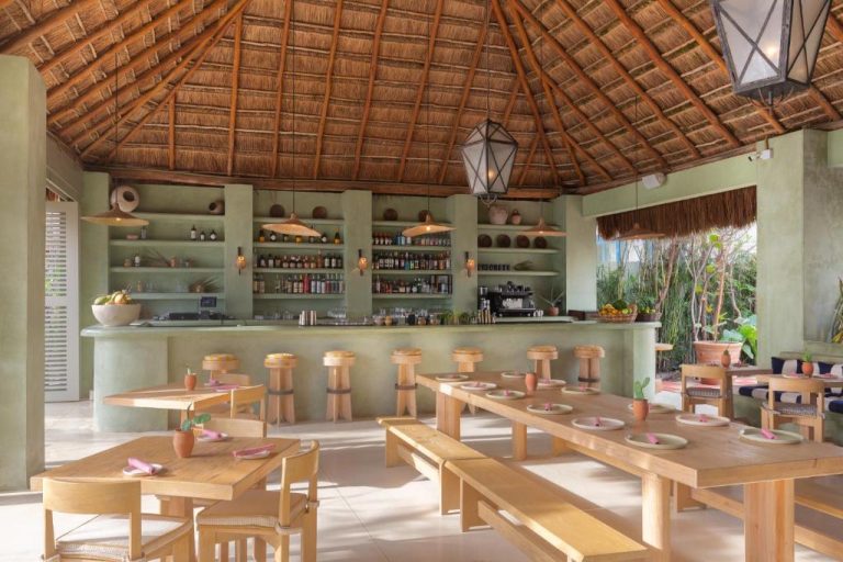 Bar restaurante con techo de palapa y mesas de madera en el Hotel Panamera