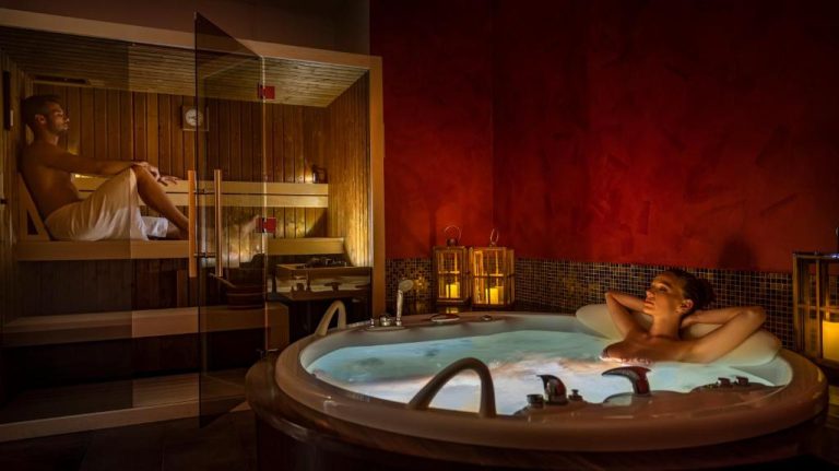 Zona spa con jacuzzi y sauna de madera del Grand Hotel Adriatic con iluminación romántica