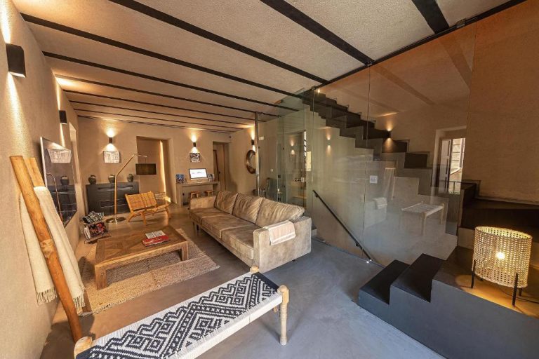 Salón con sofá, mesa de madera y elegante escalera de cristal en Casa Nostra Boutique Hotel & Spa