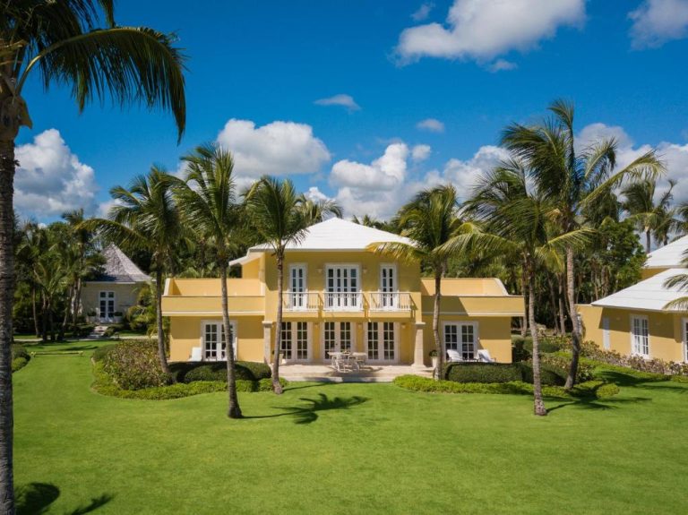 Villa exterior amarilla con jardín tropical y palmeras del exclusivo hotel Tortuga Bay en Punta Cana