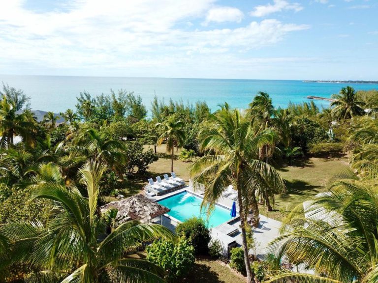 Piscina exterior rodeada de palmeras con vistas al mar turquesa en The Sunset Cove and Rainbow Room