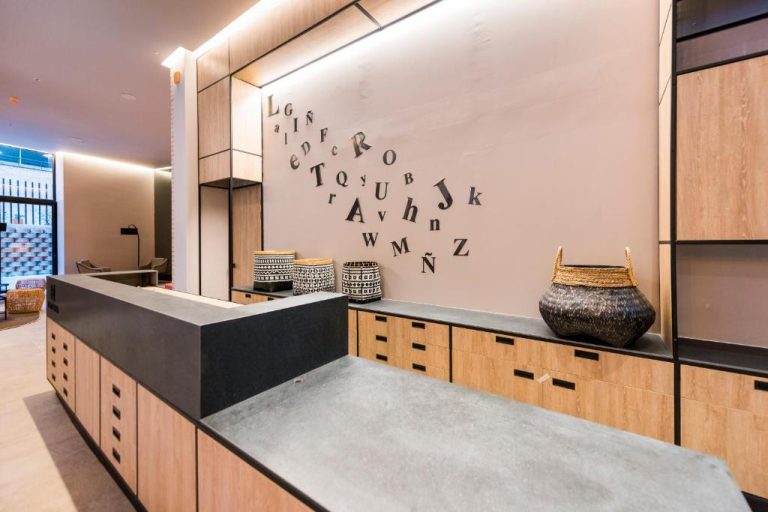 Recepción moderna del Lettera Hotel con decoración de letras en la pared y muebles de madera