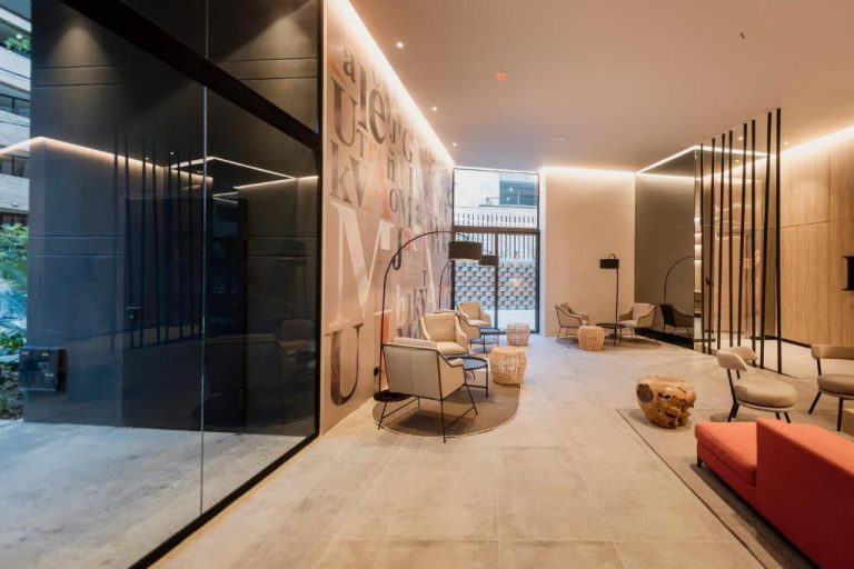 Lobby moderno del Lettera Hotel con mural tipográfico, sillones y zona de descanso con iluminación elegante