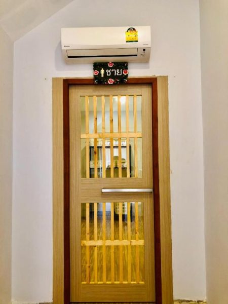 Puerta de madera con letrero en tailandés del baño masculino en Chiangkhong Teak Garden Riverfront Onsen Hotel