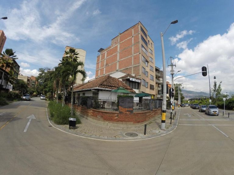 Fachada exterior y entrada del Hotel Boutique Plaza con edificio de ladrillo y terraza con sombrillas verdes