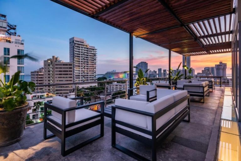 Terraza rooftop del Oz Hotel Luxury con sofás blancos, pérgola de madera y vistas panorámicas al atardecer