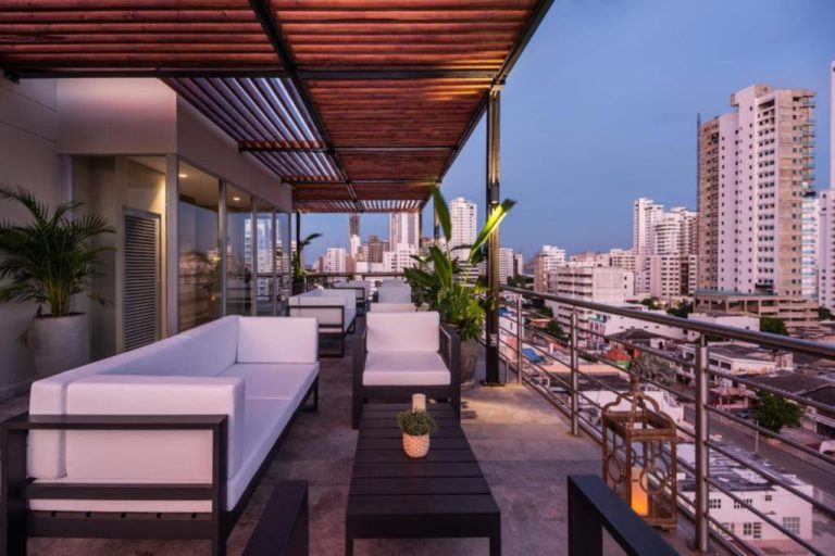 Terraza rooftop con sofás blancos y vista panorámica de la ciudad en Oz Hotel Luxury
