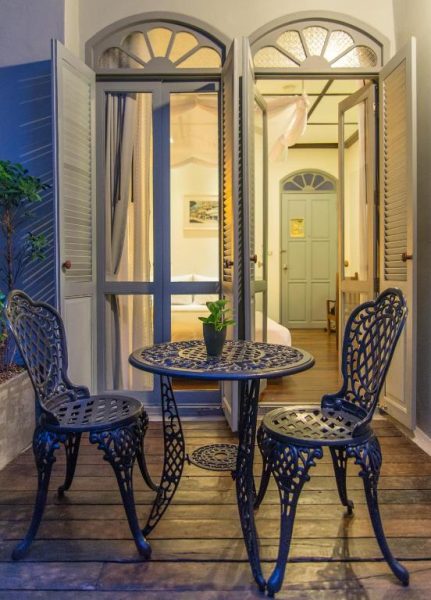 Terraza colonial con mesa y sillas de hierro forjado en The Memory at On On Hotel en Phuket