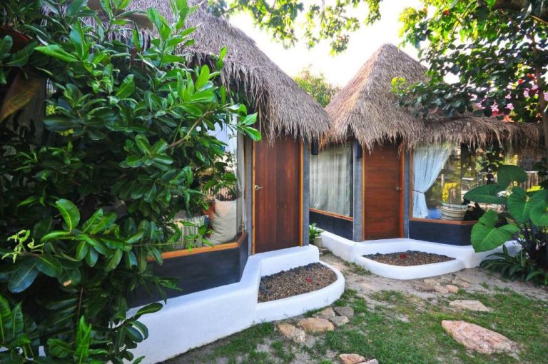 Bungalow con techo de paja y puerta de madera rodeado de vegetación tropical en Cafe'@luv22