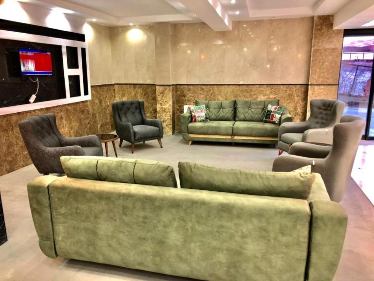 Amplio salón lobby del Grand Kum Boutique Hotel con sofás verdes y sillones grises elegantes