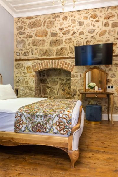 Habitación doble con pared de piedra histórica y chimenea en Hotel Lykia Old Town Antalya