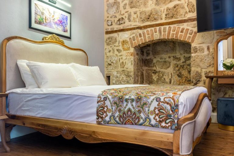 Habitación doble con cama clásica de madera y pared de piedra histórica en Hotel Lykia Old Town Antalya