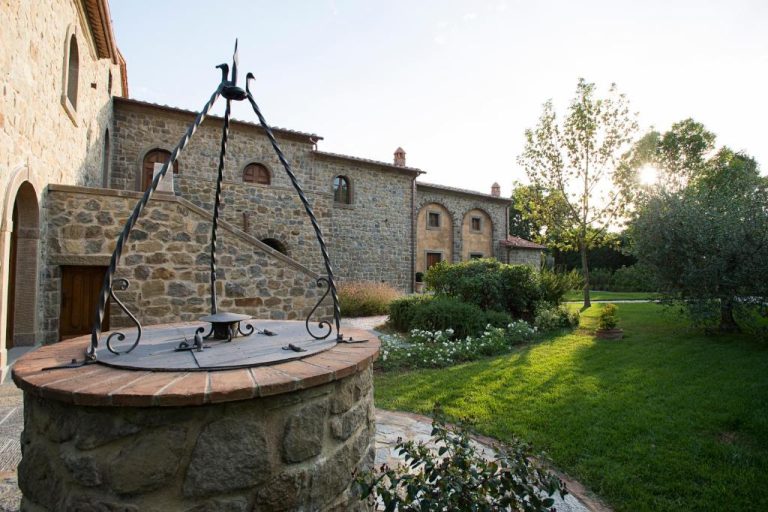 Pozo de piedra con estructura de hierro forjado en el jardín exterior del Relais La Corte dei Papi