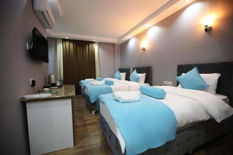 Habitación triple con camas individuales en azul y blanco del Grand Kum Boutique Hotel
