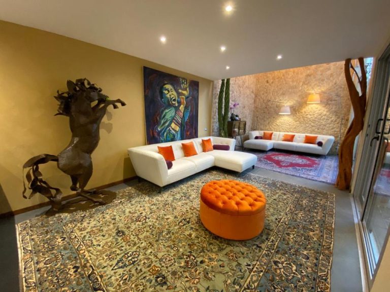 Elegante salón con esculturas, sofás blancos y obra de arte en Casarte Boutique Hotel