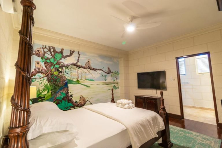 Habitación con cama de dosel y mural de monos en la selva en Sweetfield Manor Barbados