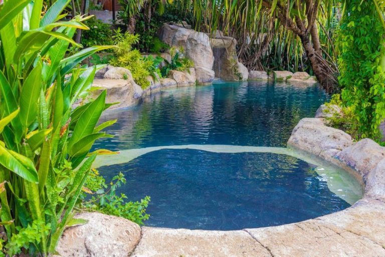 Piscina natural con cascada de roca y vegetación tropical exuberante en Sweetfield Manor Barbados