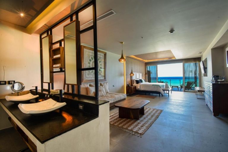 Habitación de lujo con baño abierto, sala de estar y terraza con vista al mar en Mvngata Beach Hotel